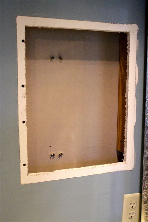 To make the recessed cavity for the cabinet, the contractor drilled a 3″ observation hole into the wall and examined the area behind it with a flashlight, looking for obstructions like plumbing lines or electrical wires. How to turn an old medicine cabinet into open shelving