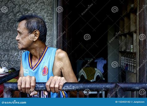 a mature filipino man stands outside the front of his home editorial image