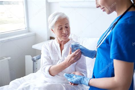 Nurse Giving Medicine To Senior Woman At Hospital Stock Photo By ©syda