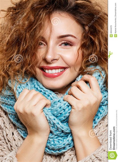 close up portrait of cheerful smiling beautiful brunette curly girl in knitted sweater and grey