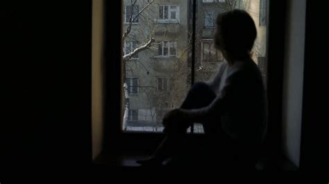 Silhouette Of Depressed Woman Sitting On The Sill And