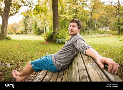 Portrait Of Barefoot Young Man Sitting On Park Bench Stock Photo Alamy