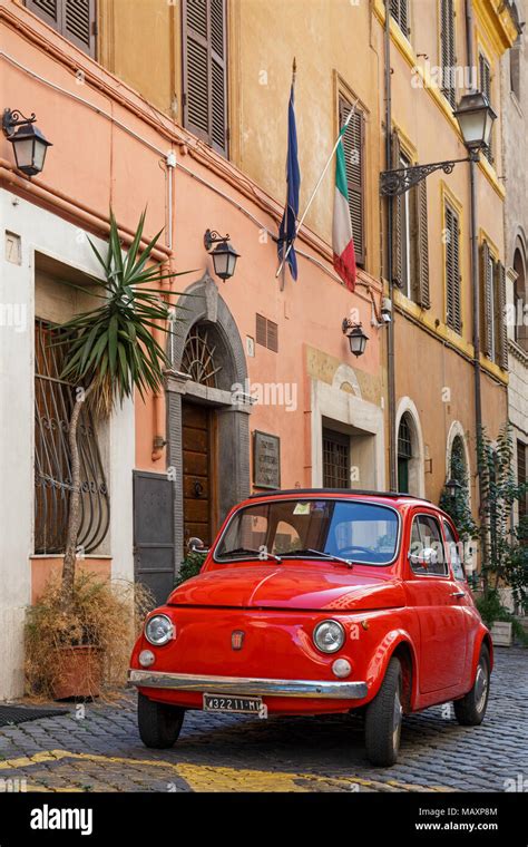 An Iconic Old Red Fiat 500 Parked In A Cobbled Street In Rome Italy