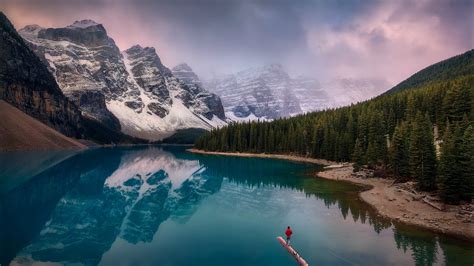 Canadian Rockies Moraine Lake With Mountain Reflection And A Man Is Standing On Broken Long Tree