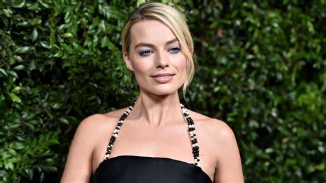 Margot Robbie Is Wearing Black Dress With A Smiley Face In Green Leaves