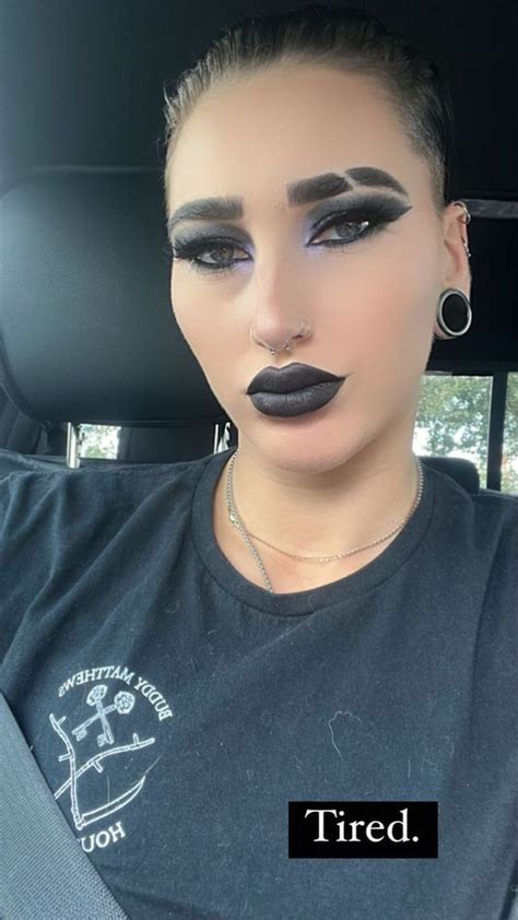 A Woman With Black Lipstick On Her Face Sitting In The Back Seat Of A Car