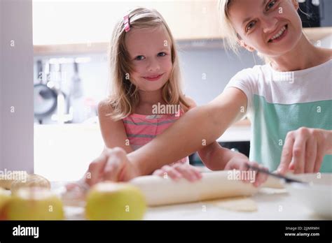 Happy Young Mother And Little Child Daughter Rolls Out Dough On Kitchen