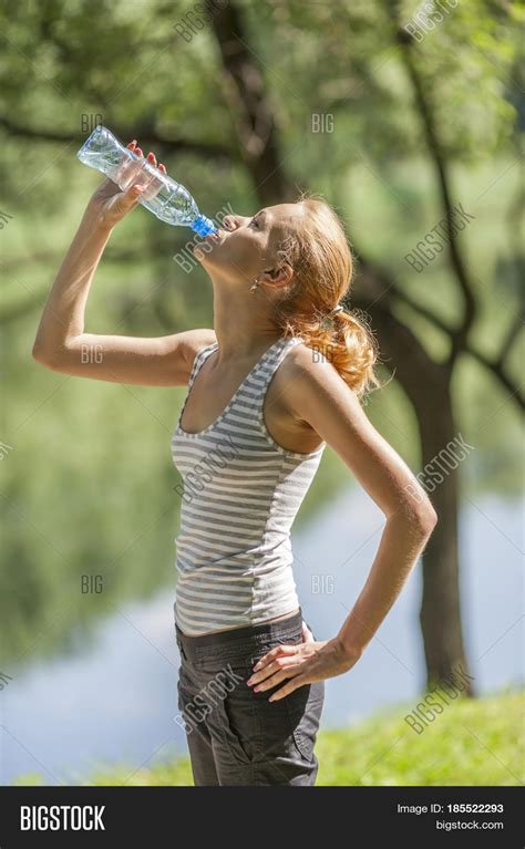 Young Woman Drinking Water Standing In Summer Park Stock Photo And Stock