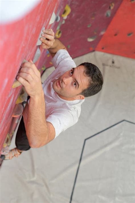 Man Climber On Artificial Climbing Wall In Bouldering Gym Stock Photo