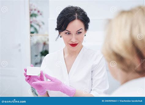 Female Cosmetologist Showing Cosmetic Cream To Client In Spa Salon