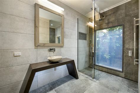 Enjoy the timeless charm of the rustic texture in floor and wall tile. Modern bathroom with switch glass, minimalist vanity, and ...