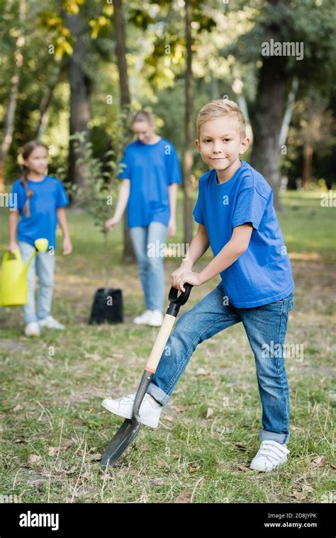 Boy Digging Ground With Shovel Near Mother And Sister With Watering Can