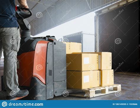 Warehouse Worker Driving Electric Forklift Pallet Jack Loading Shipment Boxes Into A Truck