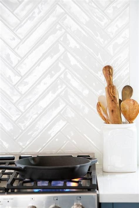 White Herringbone Backsplash Tiles Are Mounted To A Cooktop Over A
