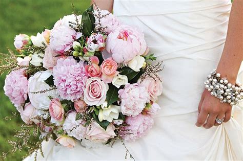 A Bride Holding A Bouquet Of Pink And White Flowers On Her Wedding Day