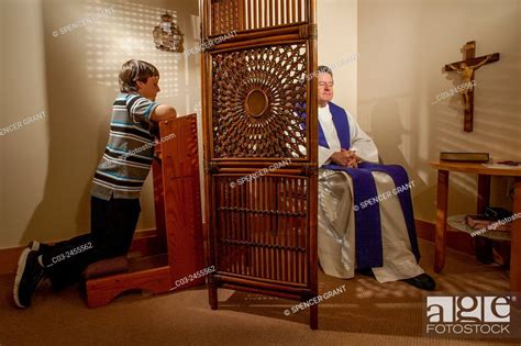 Hidden By A Screen A Priest Hears Confession From A Kneeling Boy