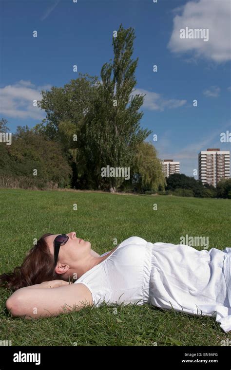 Woman Relaxes With Her Hands Behind Her Head Whilst Sunbathing In An