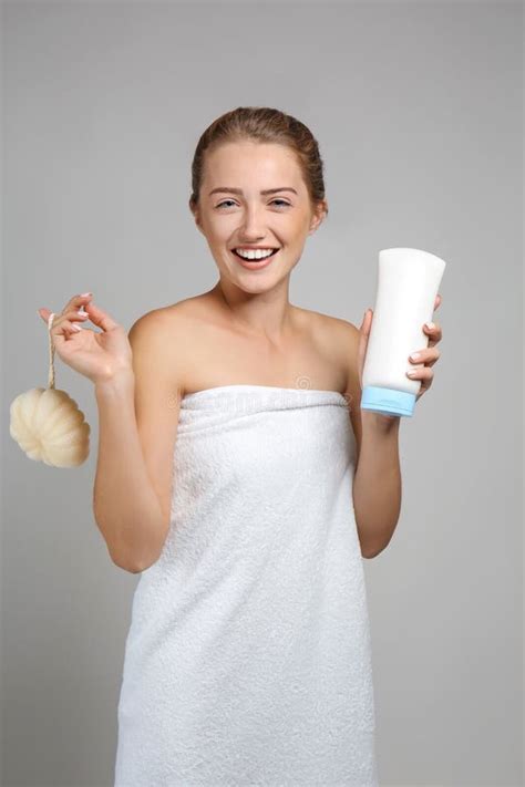Beautiful Young Woman Wrapped In Towel Holding Shower Puff And Shampoo