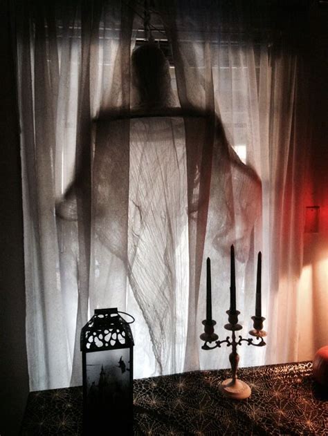 A Ghostly Woman Standing In Front Of A Sheer Curtain With Candles On The Table Next To It