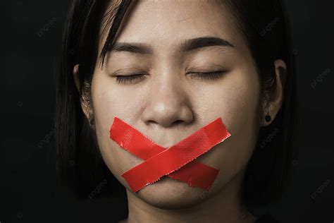 Red Tape Wrapped Around Mouth Of Blindfolded Asian Woman Photo