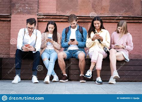 Modern Generation Group Of People Using Gadgets Sitting On Stairs