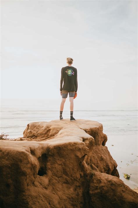 Human Person Standing At The Edge Of A Cliff In Front Of Ocean During Daytime People Image