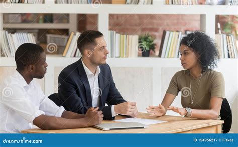 Serious Diverse Businesspeople Sitting At Table Negotiating At Business