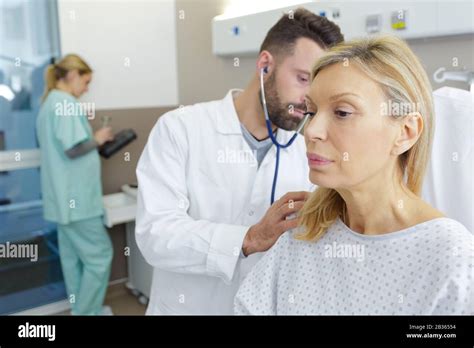 Doctor Listening Through Stethoscope To Mature Females Back Stock Photo
