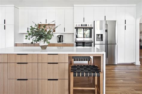 A Kitchen With White Cabinets And An Island That Has A Potted Plant On It