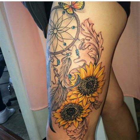 a woman s thigh with sunflowers and a dream catcher tattoo