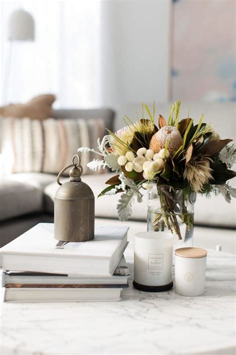 a vase with flowers on top of a table next to two books and a candle