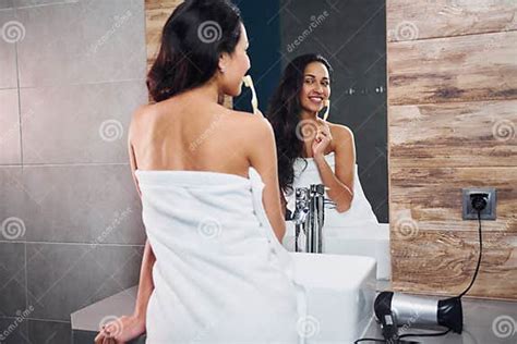 Beautiful Young Brunette Standing In Bathroom Near The Mirror And Brushing Her Teeth Stock Image