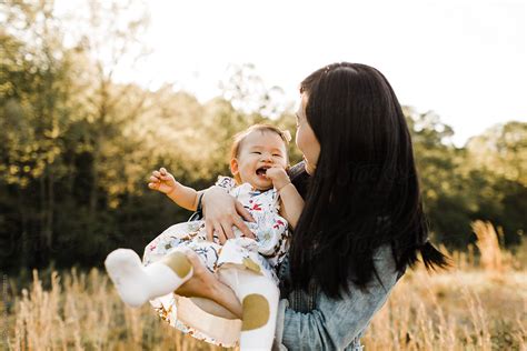 Asian Mom And Daughter Snuggling Cuddling And Playing Outdoors Del