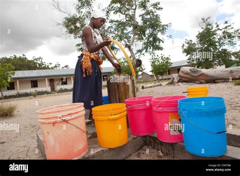 A Young Woman Fills Buckets Of Water At A Community Well Outside Dar Es