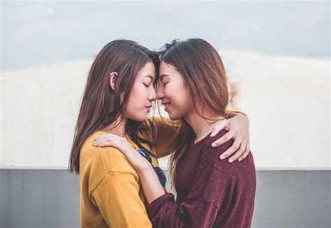asia lesben lgbtpaar zu umarmen und nase küssen sich am dach des gebäudes mit glück moment