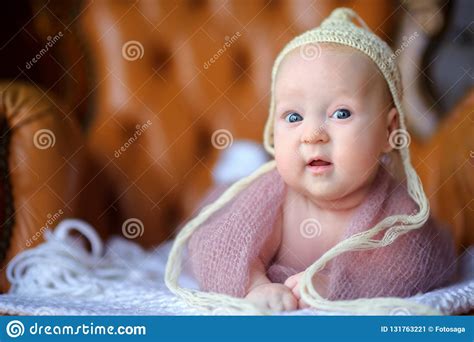 Happy Newborn Baby Lies On A Chair In A Beautiful Knitted Hat Stock