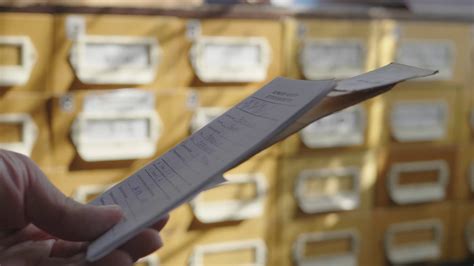 Man opens database drawer. Young librarian opens library card index. Archive, database, library 