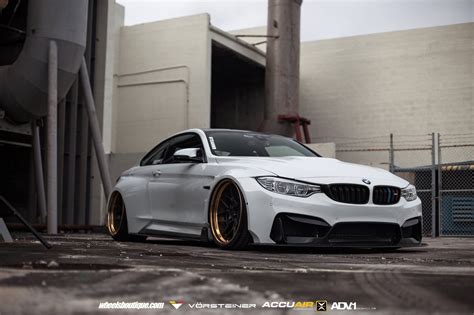 A White Car Parked In Front Of A Building With Gold Rims On Its Wheels