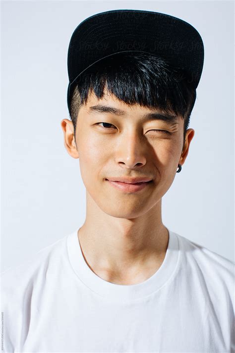 Portrait Of Young Asian Man Winking In A Cap Over White Background By Stocksy Contributor