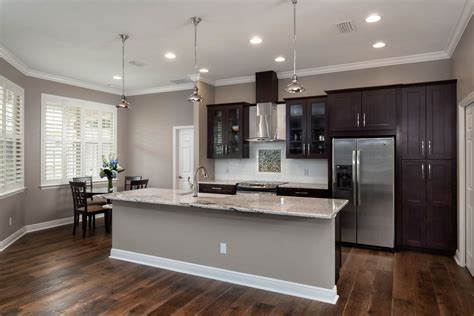 The kitchen's dominant color is white with dark wood accents on the chairs and lower island countertop. Open Concept Living With Granite, Dark Wood Cabinets, Drop Pendants, Stainless Steel Appliances ...