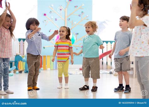 Happy Children Stand Semicircle On Floor In Kindergarten Or Day Care