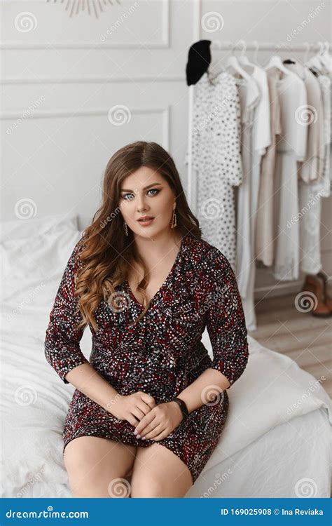 Shocked Plus Size Model Girl Sitting On A Bed And Looking In Camera