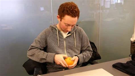 Man Struggling To Pierce Orange Peel With Fingernail Under Impression
