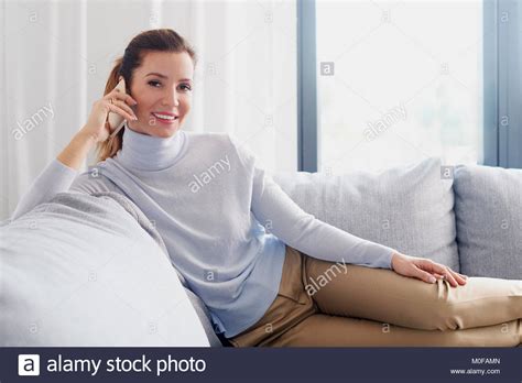 Shot Of An Attractive Mature Woman Using Her Cellphone And Making Call While Relaxing At Home
