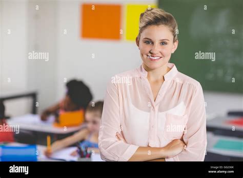 Teacher Standing With Arms Crossed In Classroom Stock Photo Alamy