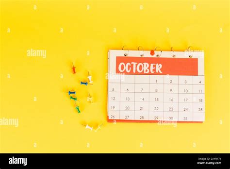 Top View Of Calendar With October Month And Office Pins On Yellow