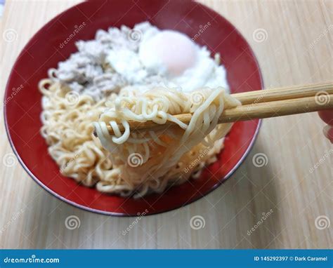 Close Up of Chopsticks Holding Instant Noodles on Blurred Boiled Egg