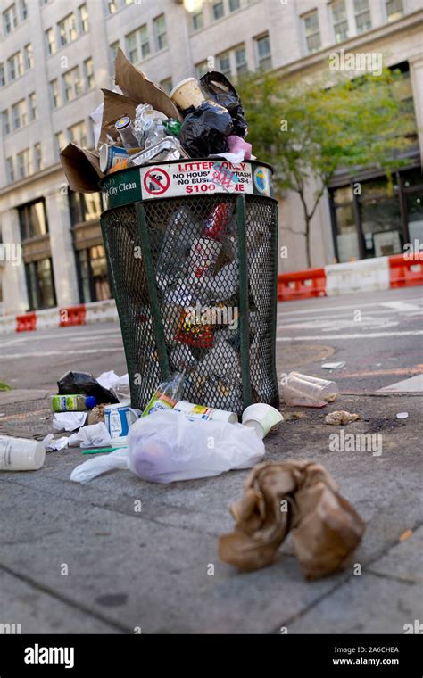 Rash Can Overflowing On Urban Sidewalk Public Waste Bin Full With