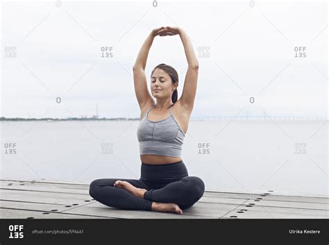 Woman Sitting With Her Arms Raised Above Her Head In A Yoga Pose Stock Photo OFFSET