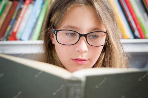 Premium Photo A Girl With Glasses Is Reading A Book